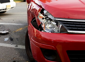 closeup of a red car with a smashed front headlight